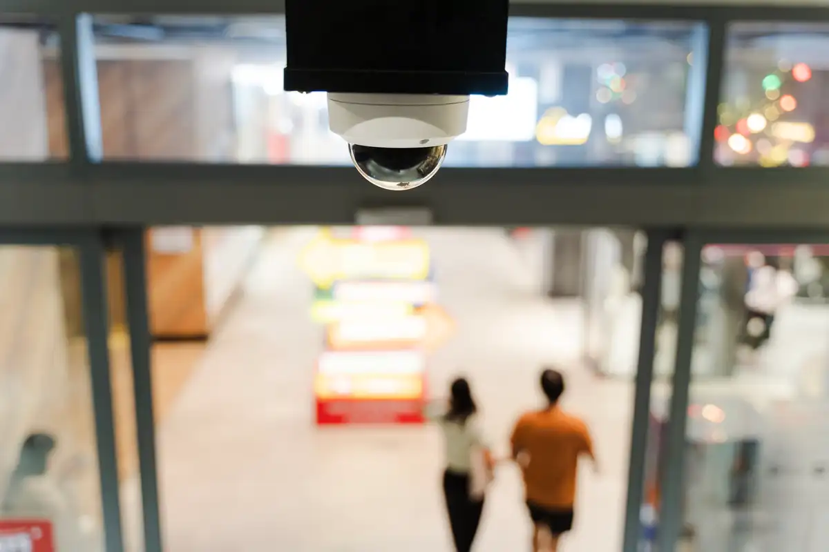 Cámara domo instalada sobre el acceso de un local con personas al fondo