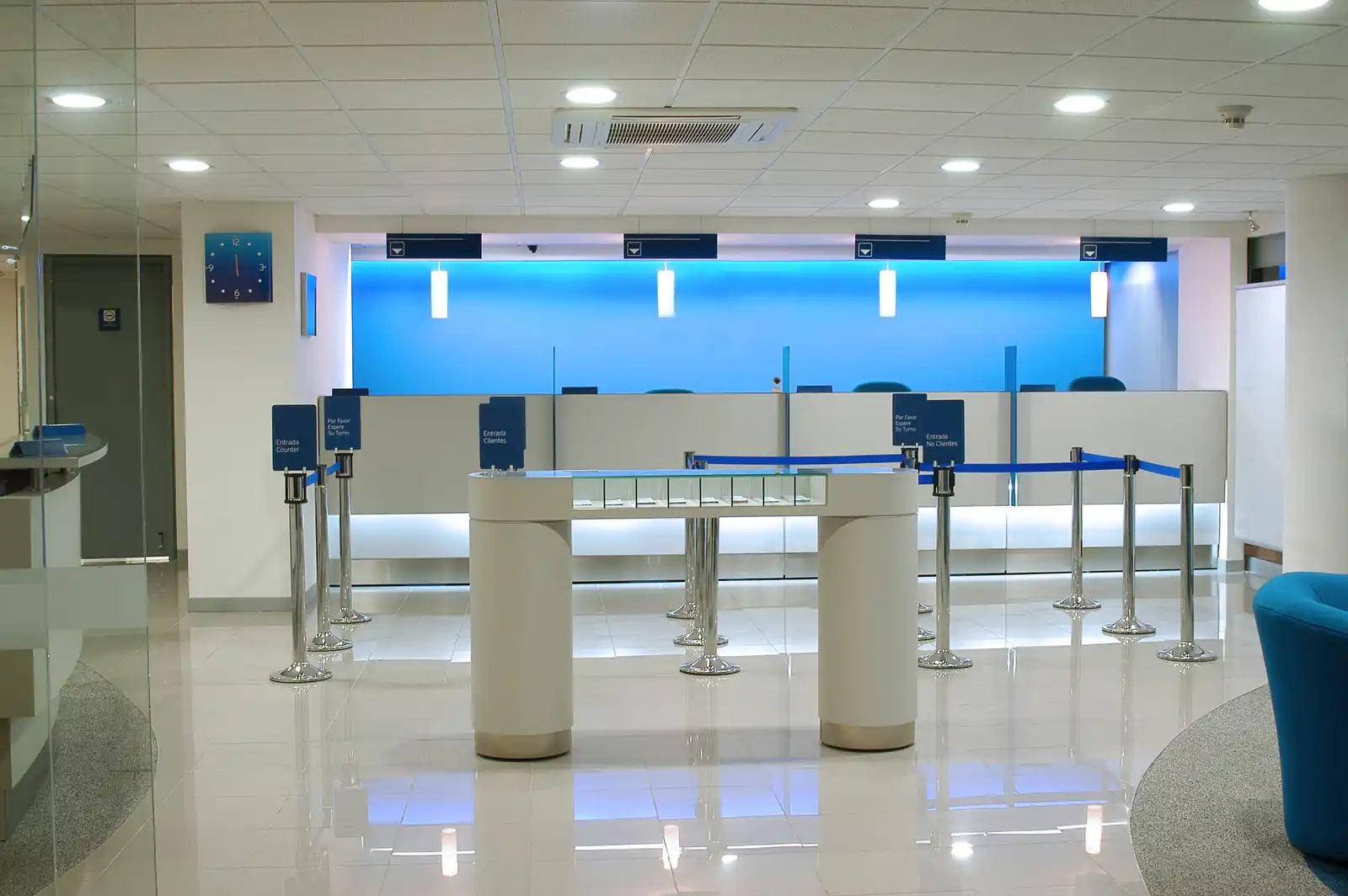 Salón de atención con mostradores, separadores de fila y asientos azules