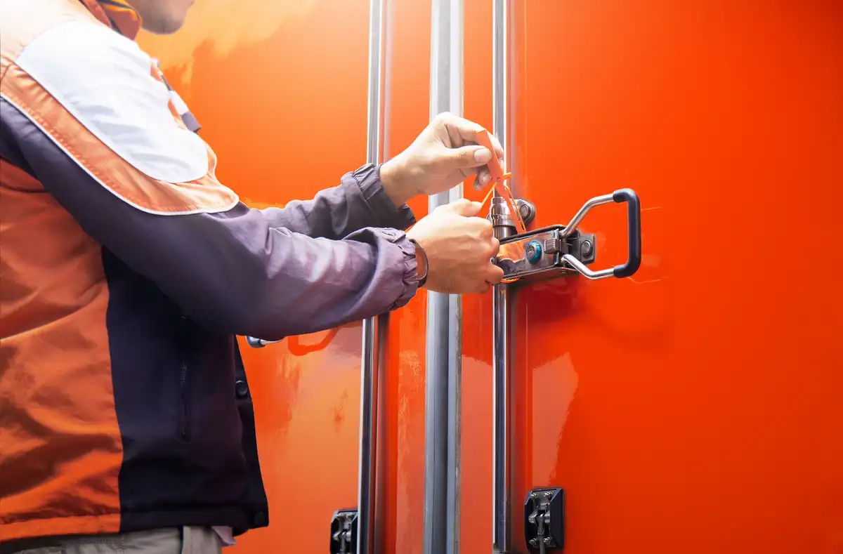 Trabajador colocando un precinto en las puertas de un vehículo de carga